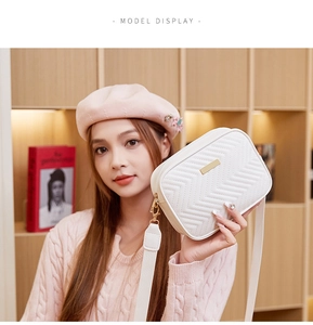 Close-up of a white quilted shoulder bag with wave stitching and a gold metal buckle