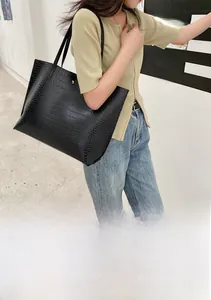 Vue détaillée du sac cabas noir à motif crocodile montrant sa grande capacité sur modèle