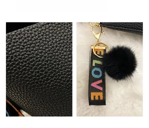 Détail du sac cabas noir en cuir grainé avec fermoir doré et breloque ruban LOVE