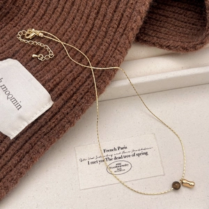 French vintage tiger eye stone pendant necklace on textured fabric background