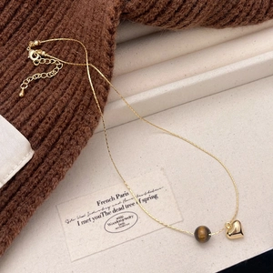 French vintage tiger eye and gold heart pendant necklace on a beige linen background