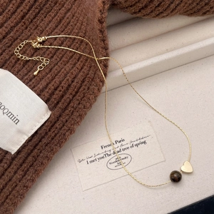 Tiger eye stone necklace with gold-plated heart pendant on a warm knit fabric