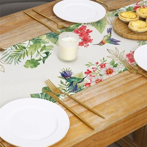 Floral table runner with hummingbirds on a wooden dining table with elegant tableware