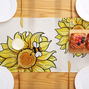 Linen table runner with sunflower and bee prints on a light wooden dining table