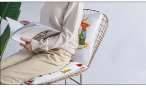 Detail of Christmas deer cushion cover on golden chair with autumnal maple leaf design