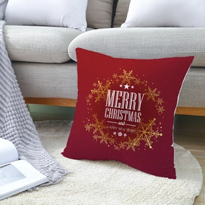 Rotes Weihnachtskissen mit goldenen Schneeflocken und Gruß auf weißem Plüschteppich