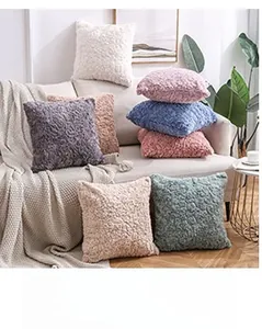 Detail of embossed solid color plush pillow covers in rose texture stacked on a sofa