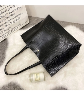 Détail d'un sac cabas noir avec motif crocodile et fermeture par bouton pression doré