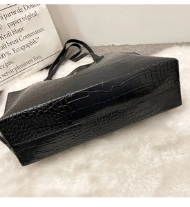 Gros plan sur la texture crocodile du sac cabas noir sur un tapis blanc