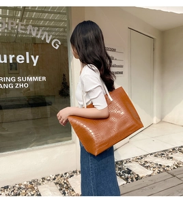 Sac cabas marron à motif crocodile et bretelles blanches porté par un mannequin dans la rue