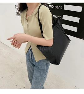 Gros plan du sac cabas noir à motif crocodile porté à l'épaule pour un style de bureau épuré