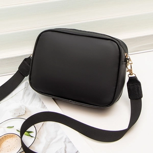 Black embroidered camera bag with wide strap and gold hardware on white pedestal