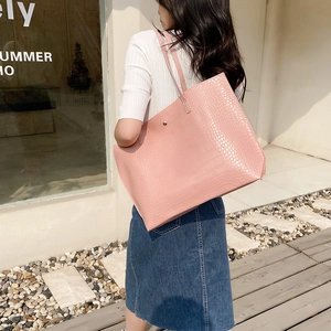 Sac cabas rose en similicuir avec texture crocodile et boucle sur un mannequin femme