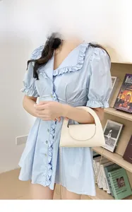 Gros plan du mini sac crème en cuir texturé avec bandoulière chaîne dorée sur mannequin