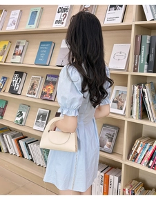 Petit sac à main blanc cassé avec chaîne dorée assorti à une robe d'été bleue