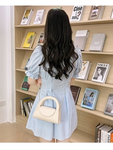 Sac bandoulière chic crème avec chaîne et poignée présenté dans une scène de style