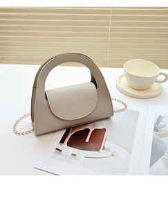 Détail du petit sac beige avec texture grainée et fine bandoulière en chaîne dorée