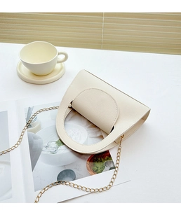 Détail du sac en cuir blanc crème avec texture litchi et bandoulière chaîne dorée