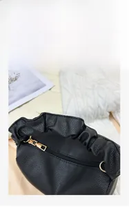 Close-up of black lychee grain leather handbag with cloud pleats and gold zipper