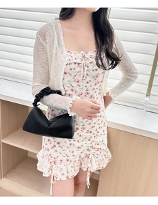 Close-up of soft pleated black leather pillow bag with stylish chain handle and floral dress
