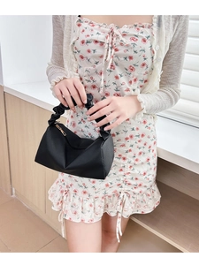 Detail of black pleated cloud bag with scrunchie handle and gold zipper on a floral dress