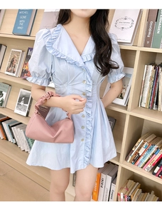 Close-up of soft pink leather pillow bag with pleated handle on a light blue dress