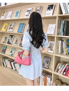 Detail of pink pleated handbag paired with light blue puff sleeve dress in a study room
