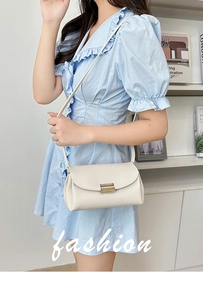 Detail of lychee textured leather crossbody bag with metal buckle on blue dress