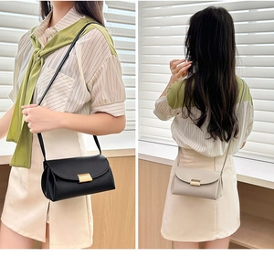 Detail of minimalist crossbody bag with textured faux leather and gold metal lock