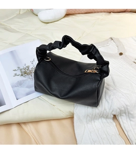 Detail of black lychee grain texture and soft pleated handle on a fashion handbag