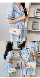 Detail of cream crossbody bag with lychee texture and gold metal buckle lock