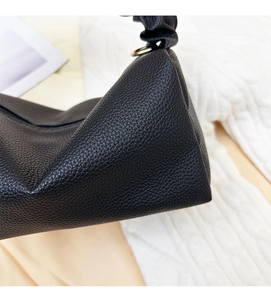 Close-up of black lychee leather texture and ruched strap detail on the stylish handbag