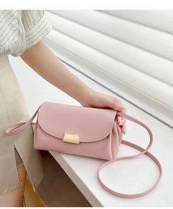 Detail of light pink lychee leather crossbody bag with golden textured buckle and thin strap