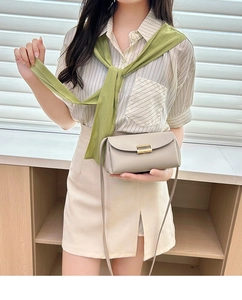 Detail of beige leather crossbody bag featuring gold metal clasp and pebble texture finish