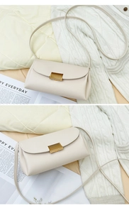 Close-up of off-white lychee pattern PU leather bag with golden metal buckle and thin strap
