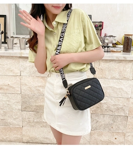 Detail of black quilted crossbody bag with a wide fashion strap and tassel zipper