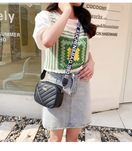 Detail of black quilted crossbody bag with stylish letter print wide shoulder strap
