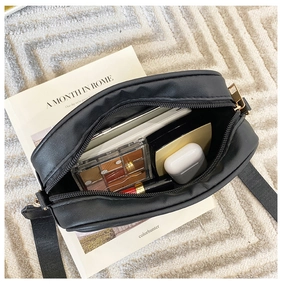 Internal storage detail of black leather crossbody bag showing makeup and accessories