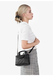 Vue détaillée du sac seau noir matelassé avec coutures géométriques porté par un mannequin