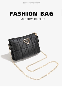 Close-up of black quilted crossbody bag with heart-shaped gold buckle and chain