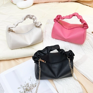 Three pleated leather pillow bags in beige, pink, and black with elegant gold chains