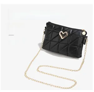 Close-up of black quilted envelope bag featuring a gold heart clasp and chain straps
