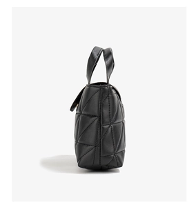 Détail du sac à main noir matelassé géométrique avec coutures triangles et poignée