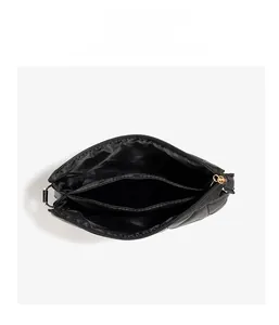 Internal detail of quilted envelope bag featuring three compartments and gold zipper