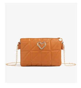Detail of a brown quilted messenger bag with heart-shaped gold buckle and chain