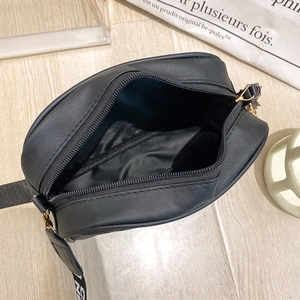 Black quilted crossbody camera bag with wide lettered strap and gold zipper detail
