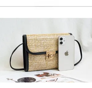 Detail view of woven straw shoulder bag featuring black leather trim and golden metal clasp