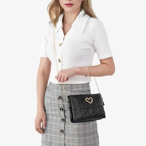 Quilted black shoulder bag with gold heart clasp and metal chain strap on model