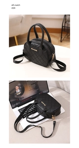 Detail view of black quilted crossbody bag with gold logo on a laptop workspace