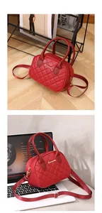 Close-up of red quilted handbag with gold hardware and adjustable strap on a white laptop